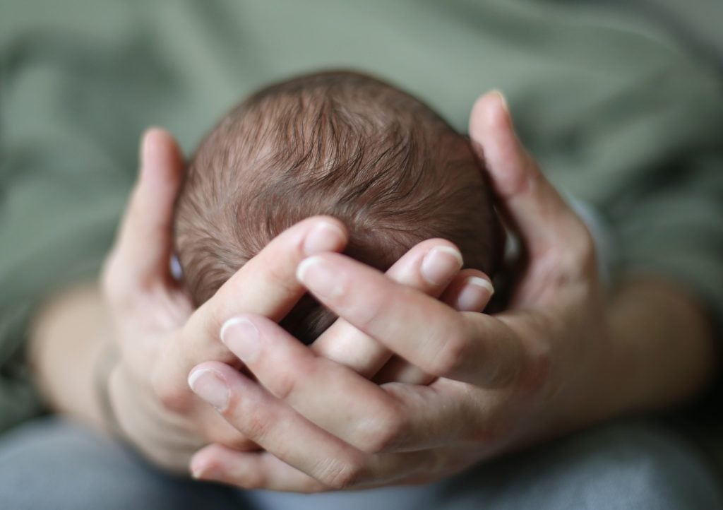 A head of a new born in his mum's hand